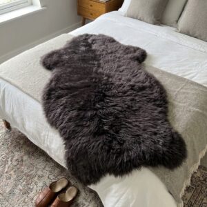 Großes dunkelbraunes Schaffell als kuscheliger Überwurf für das Bett